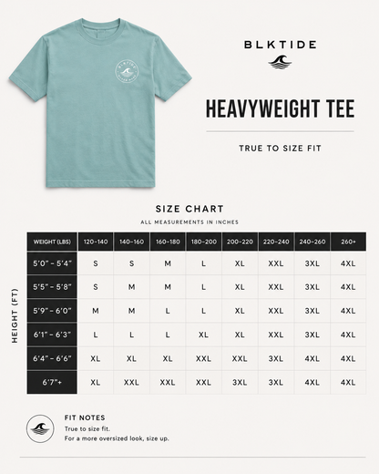 A light blue Blktide Heavyweight Tee shown on a clean white background above a size chart and fit notes. The chart lists weight and height ranges with corresponding size labels from S to 4XL, and includes a small circular chest logo on the shirt.